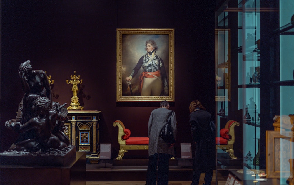homem na jaqueta do terno preto de pé ao lado da mulher na pintura do vestido dourado