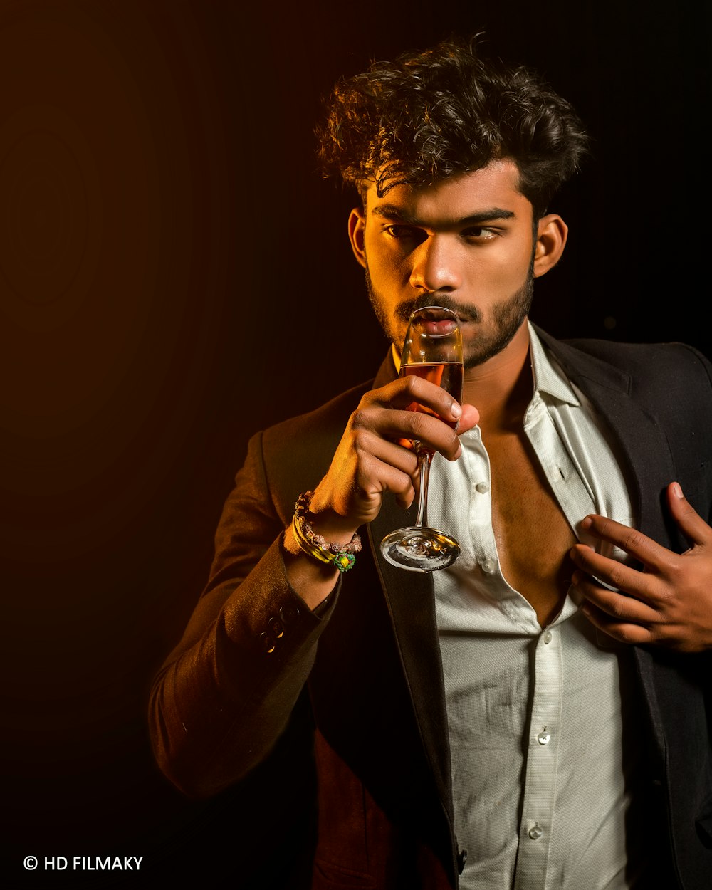 man in black suit holding clear drinking glass