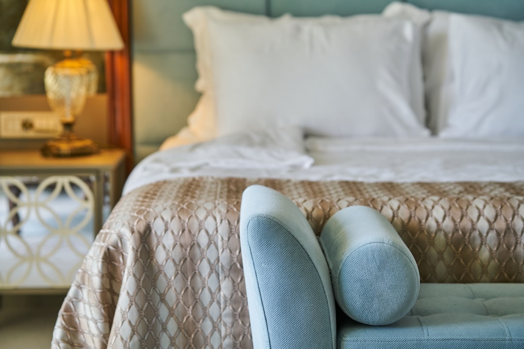 person in blue denim jeans sitting on white and brown bed linen