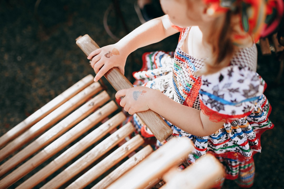 woman in white red and blue floral dress holding brown wooden fence