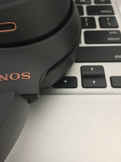 A close-up of headphones resting on a laptop keyboard with music software open.