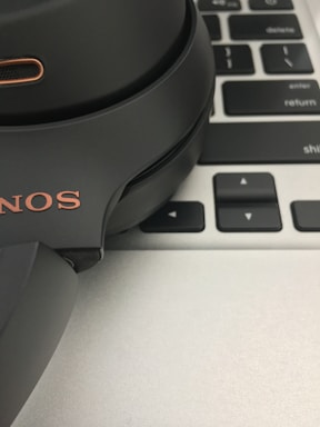 Close-up of a person typing on a laptop with headphones nearby.