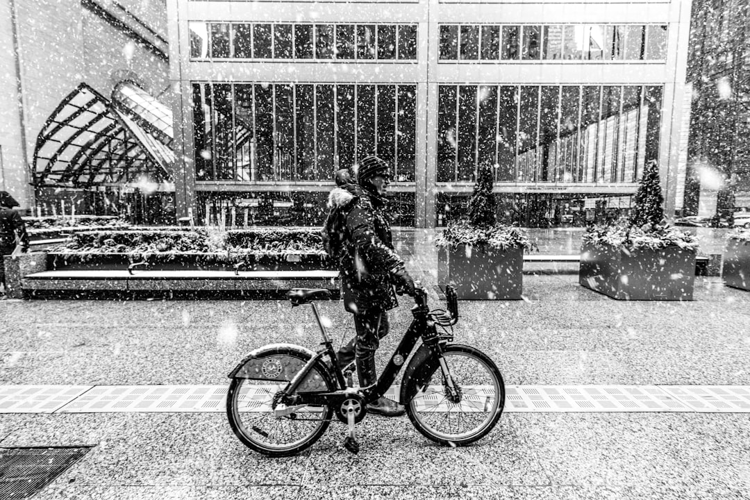 grayscale photo of man riding bicycle