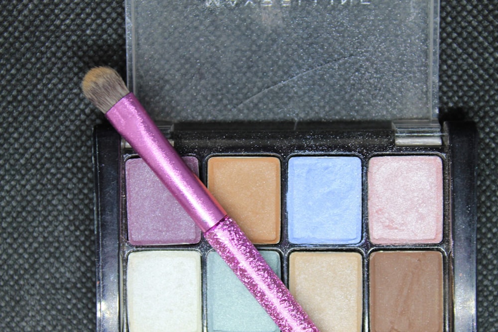 purple makeup brush on black textile