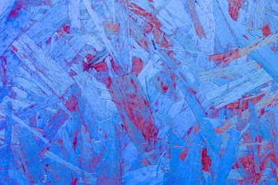 An abstract composition of overlapping wooden textures in shades of blue with accents of red, creating a dynamic and layered effect.