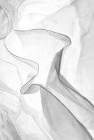 Soft fabric folds of a modest dress highlighted by natural light in a serene setting.