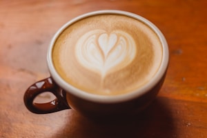 white ceramic mug with brown and white heart shaped coffee