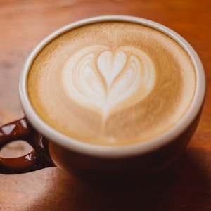 white ceramic mug with brown and white heart shaped coffee