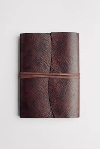 A close-up of a sleek, leather-bound notebook with a textured cover and elegant stitching.