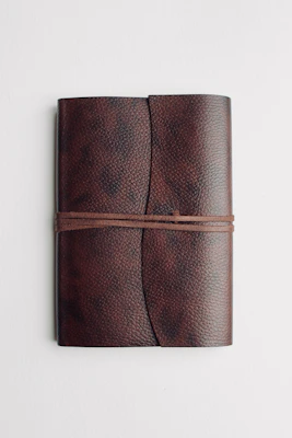 A close-up of a sleek, leather-bound notebook with a textured cover and elegant stitching.