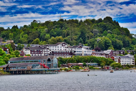 white and red house near green trees and body of water during daytime in Puerto Varas Chile