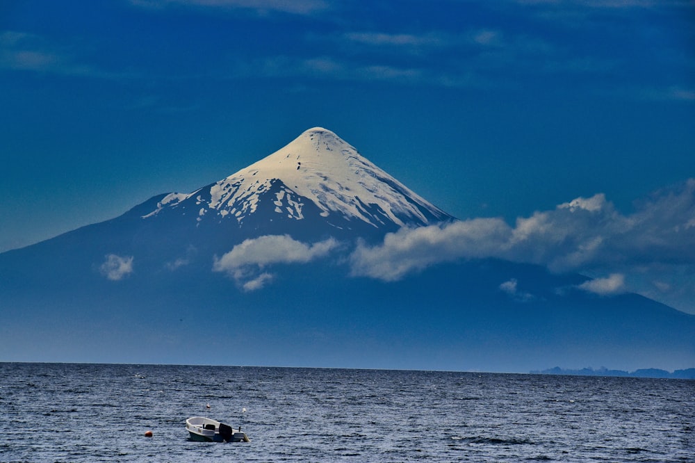 white boat on sea near snow covered mountain under blue sky during daytime