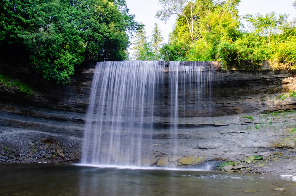 waterfalls in the middle of green trees during daytime