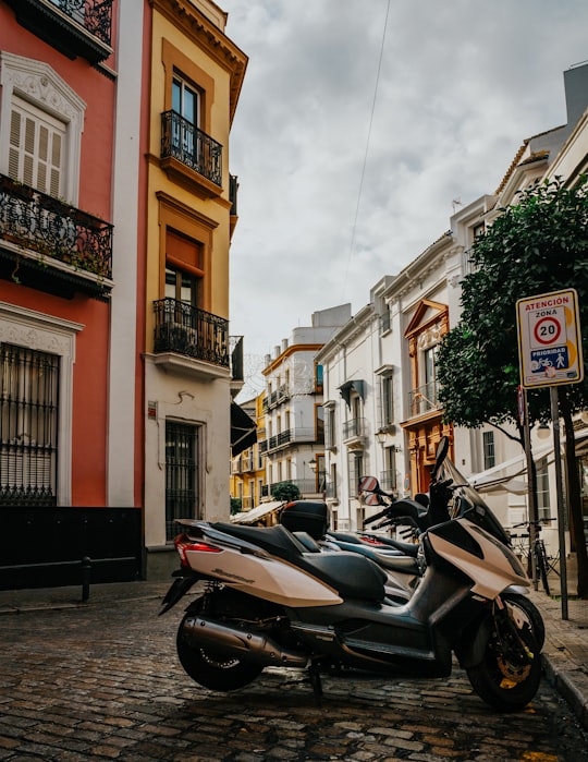 black motor scooter parked beside brown concrete building during daytime in Sevilla Spain