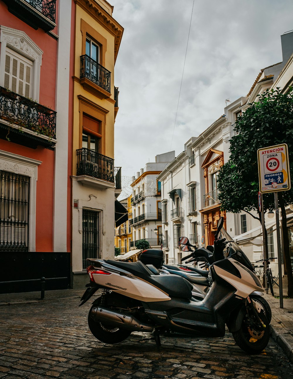 black motor scooter parked beside brown concrete building during daytime