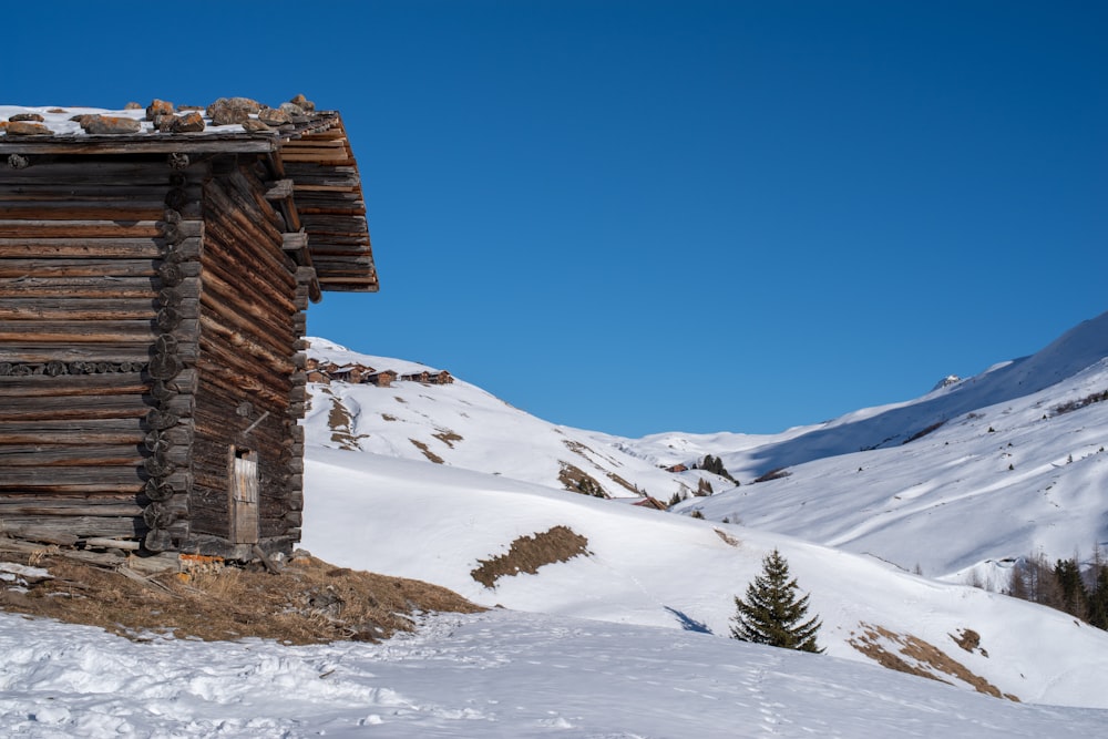 brown wooden house on snow covered ground under blue sky during daytime