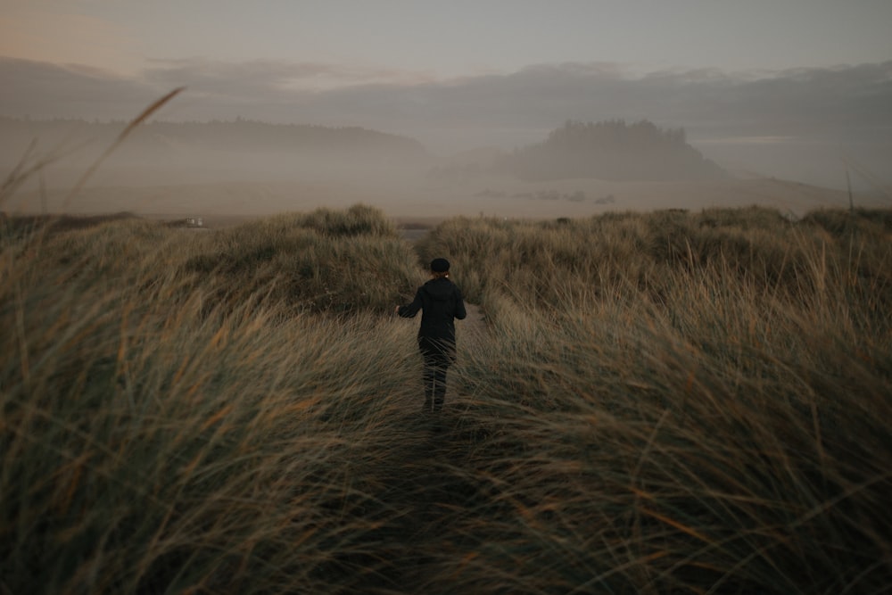 a man standing on top of a grass covered field