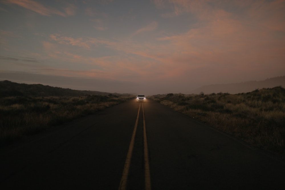 black asphalt road between green grass field during daytime