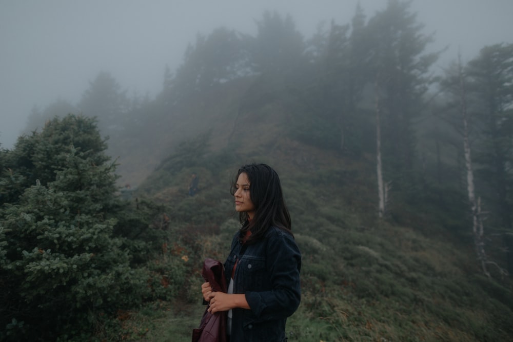 a woman standing on a hill in the fog