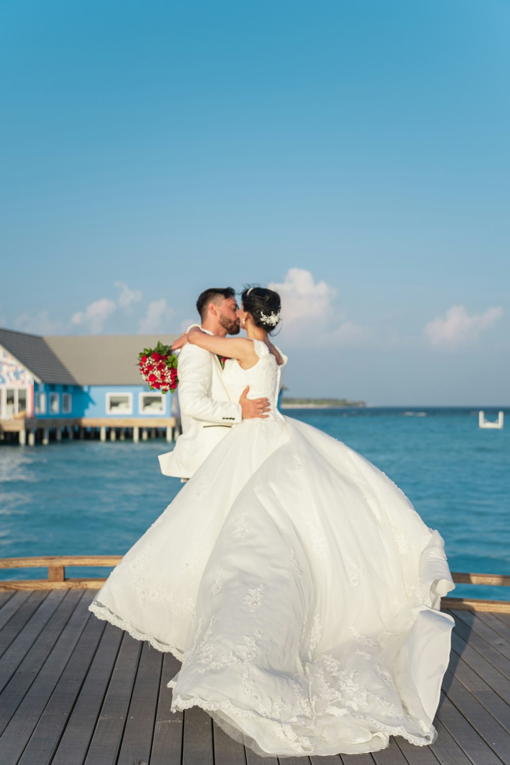 Braut und Bräutigam küssen sich tagsüber auf dem Dock