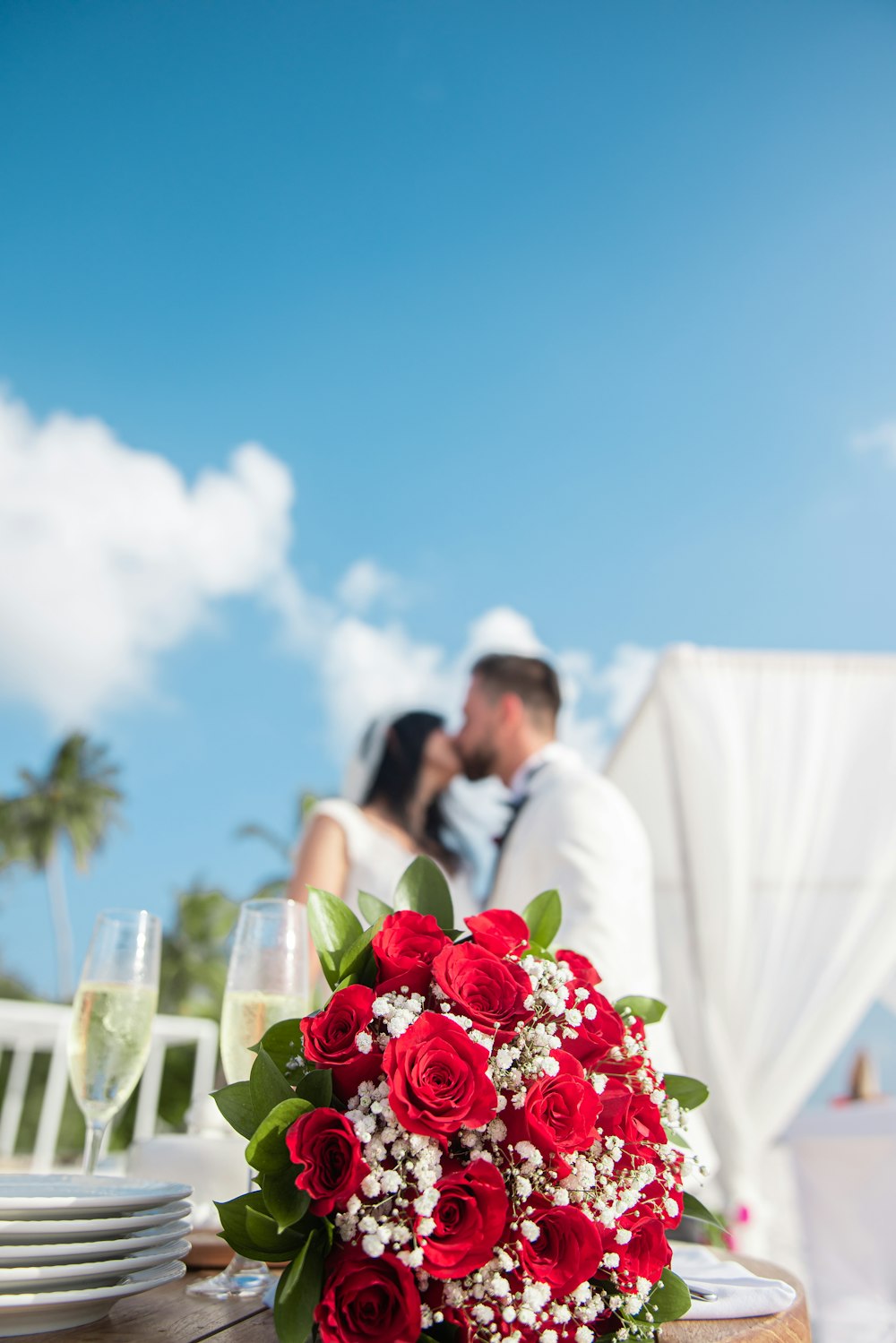 Frau im weißen Hochzeitskleid mit rotem Rosenstrauß