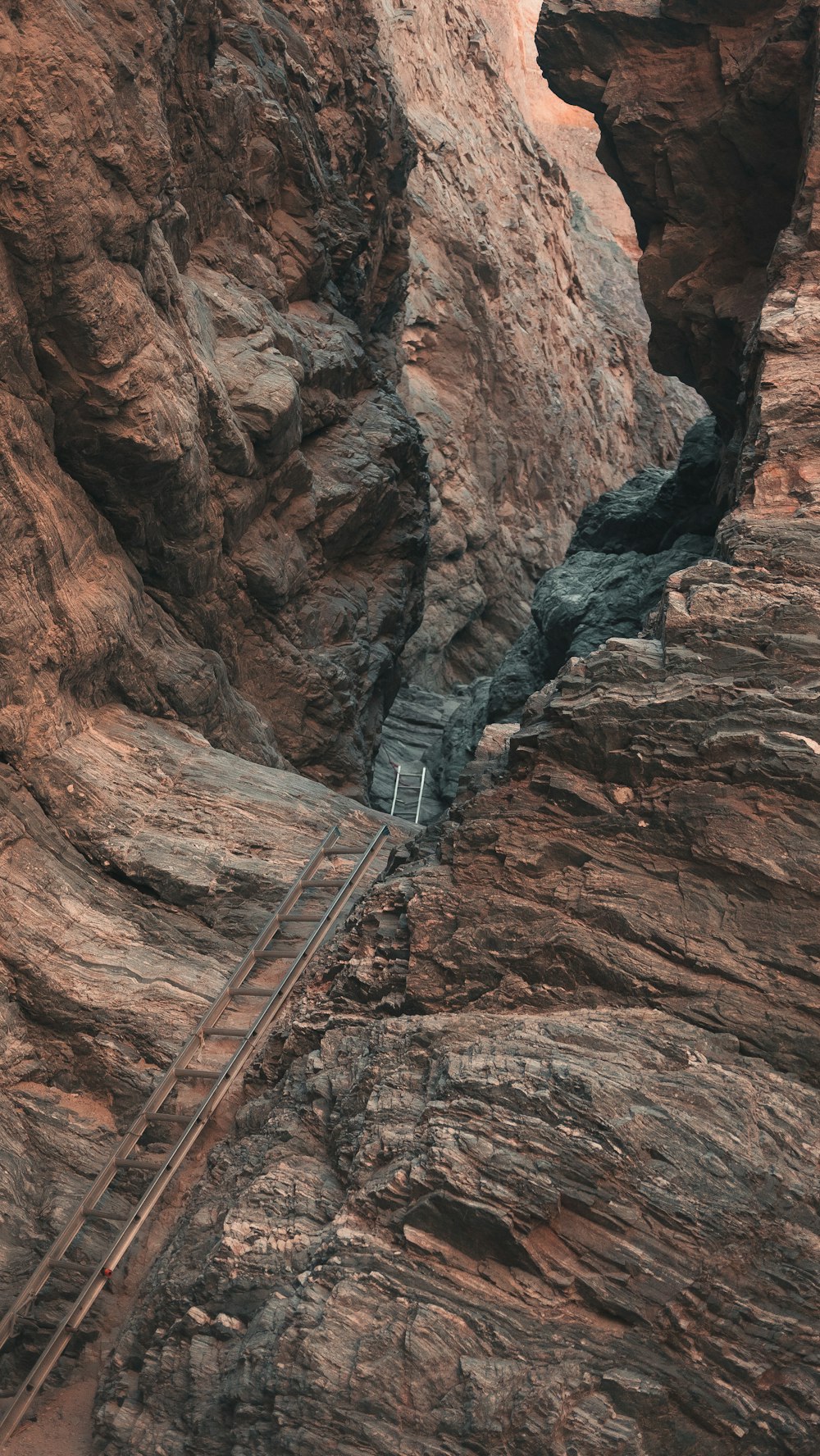 Puente de metal gris en la montaña rocosa marrón durante el día