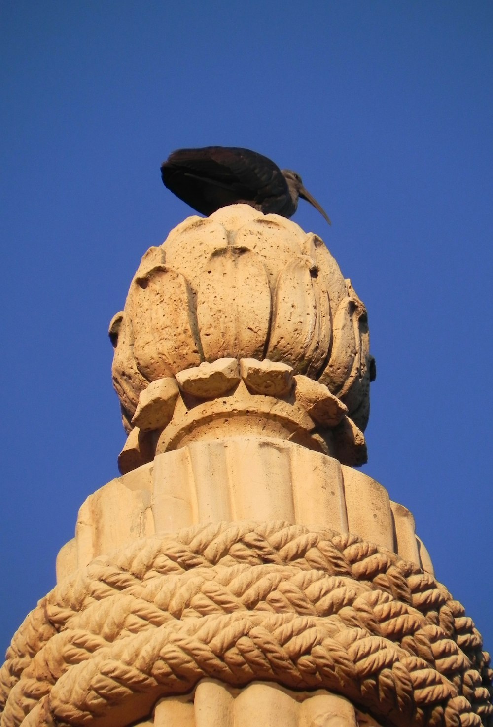茶色のコンクリート像に黒い鳥