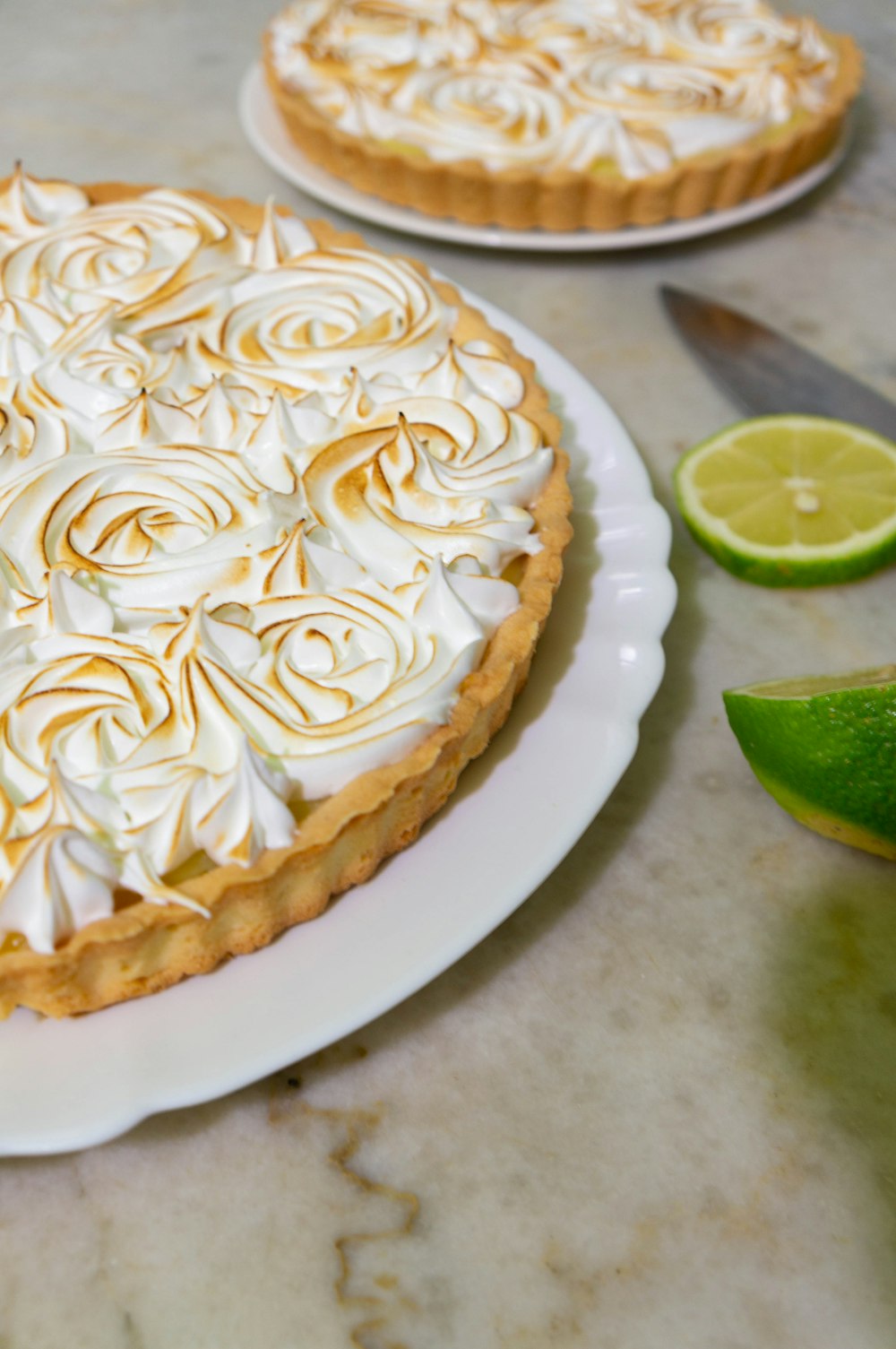 white icing cake with sliced of green citrus fruit on white ceramic plate