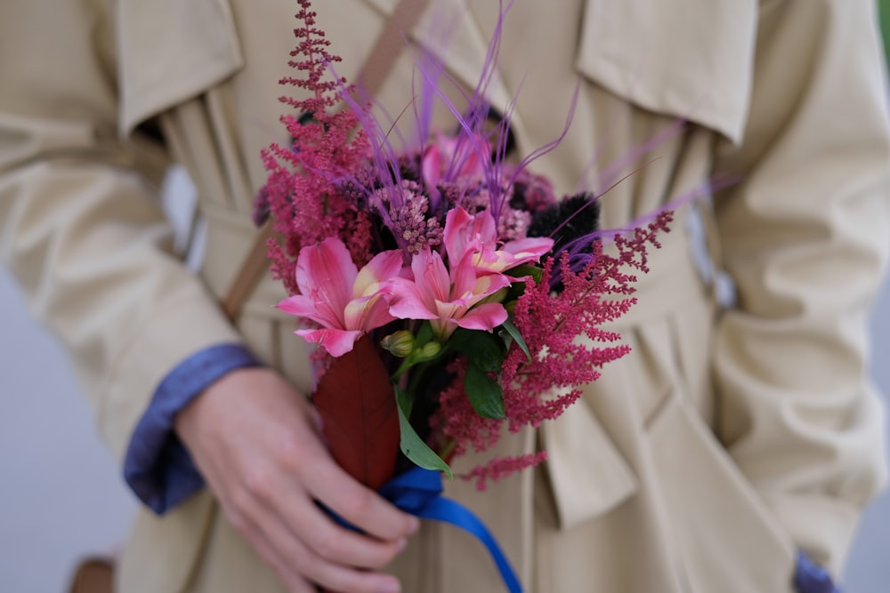 person holding pink and white flower bouquet