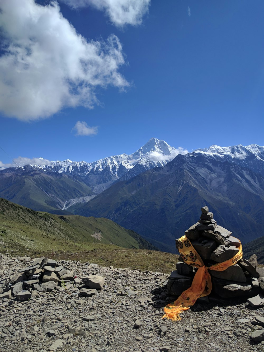 person in brown jacket sitting on rock near mountain under blue sky during daytime