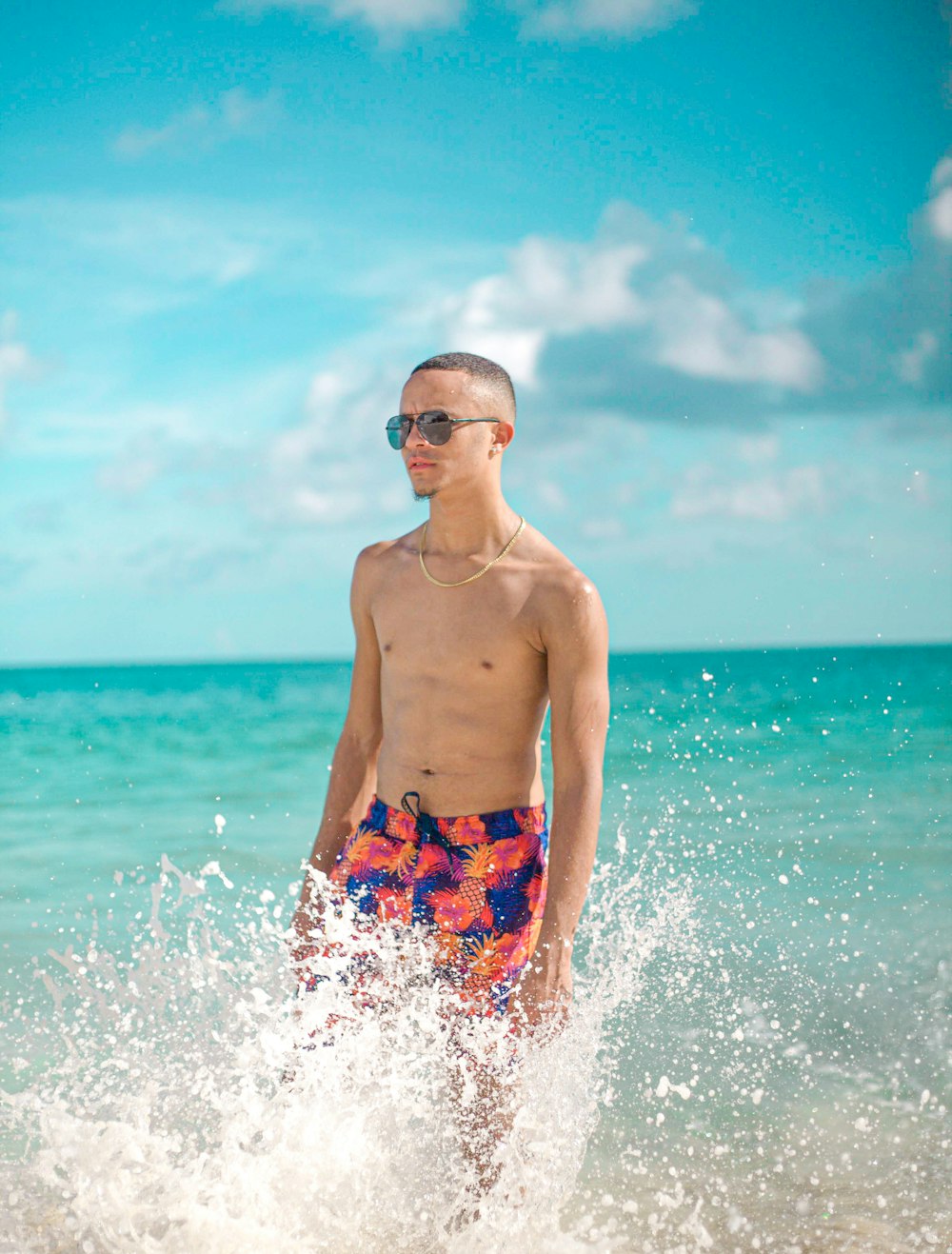 man in blue and red shorts standing on sea water during daytime