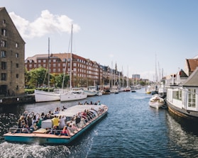people riding on boat on water near buildings during daytime