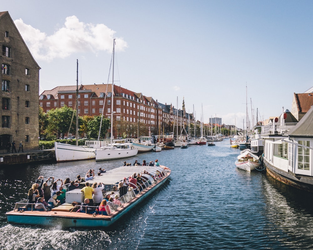 people riding on boat on water near buildings during daytime