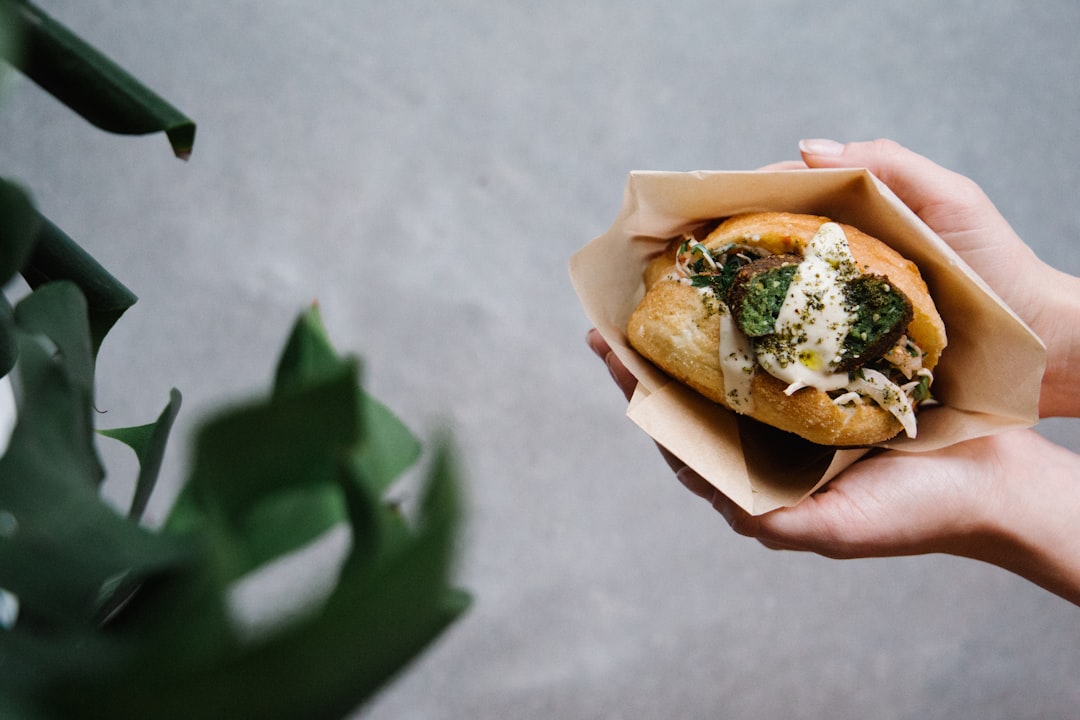 person holding burger with lettuce