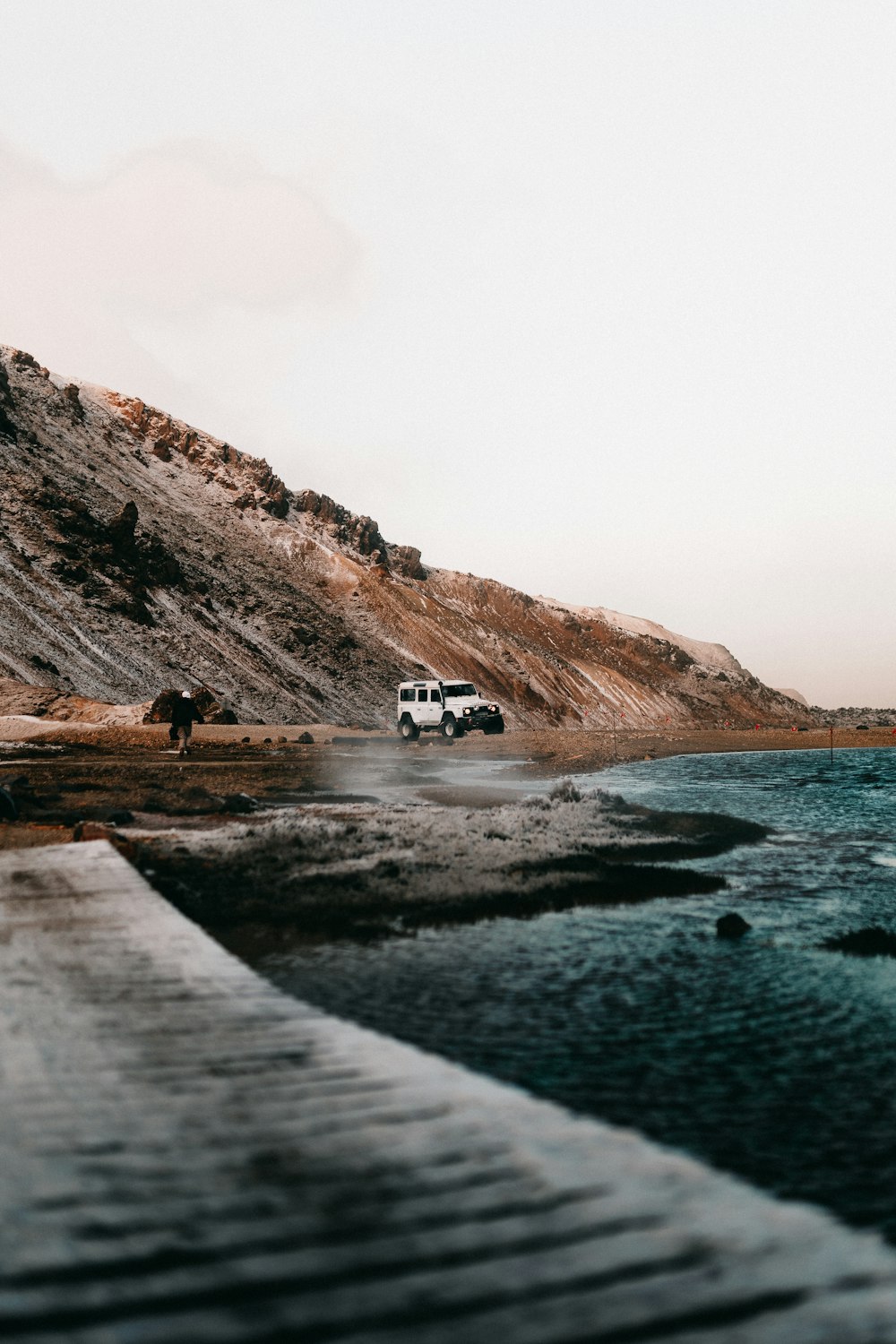 white van on brown field near body of water during daytime