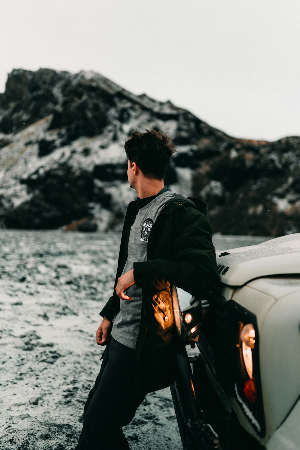 man in black jacket and black pants standing beside white car during daytime