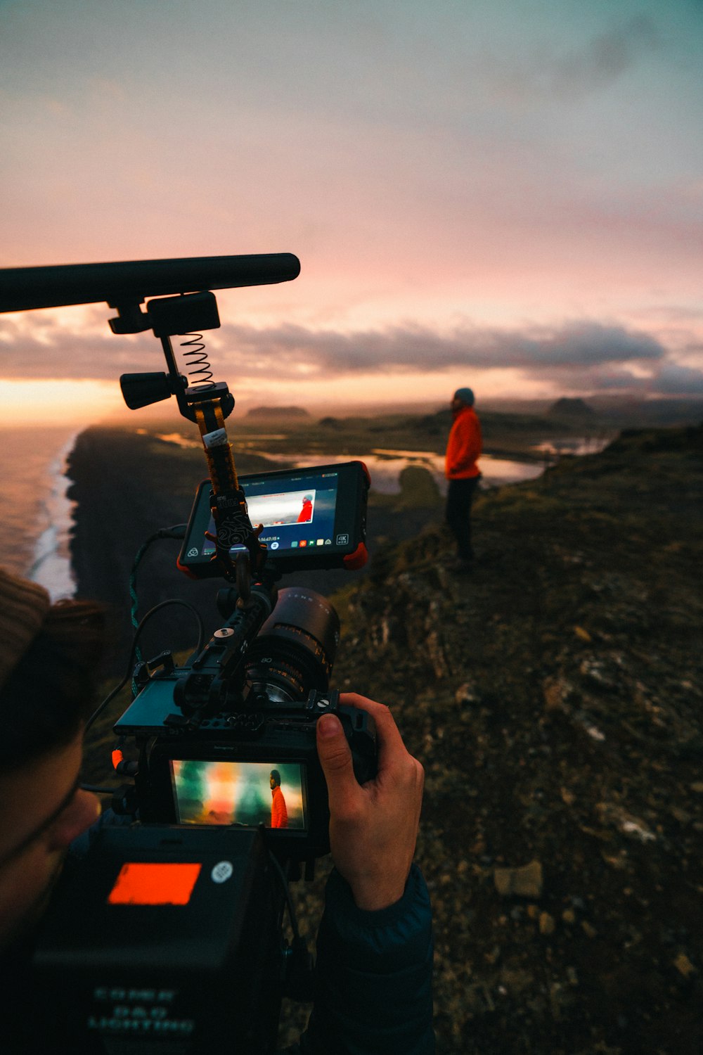 person holding black dslr camera taking photo of body of water during sunset