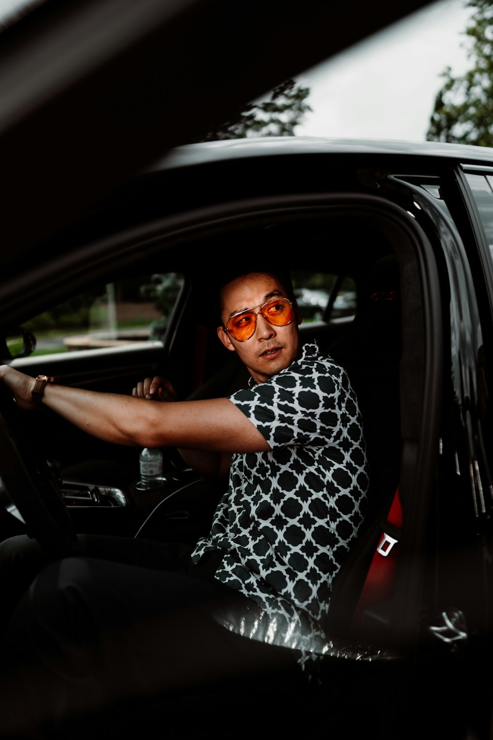 woman in black and white dress wearing black framed eyeglasses sitting inside car