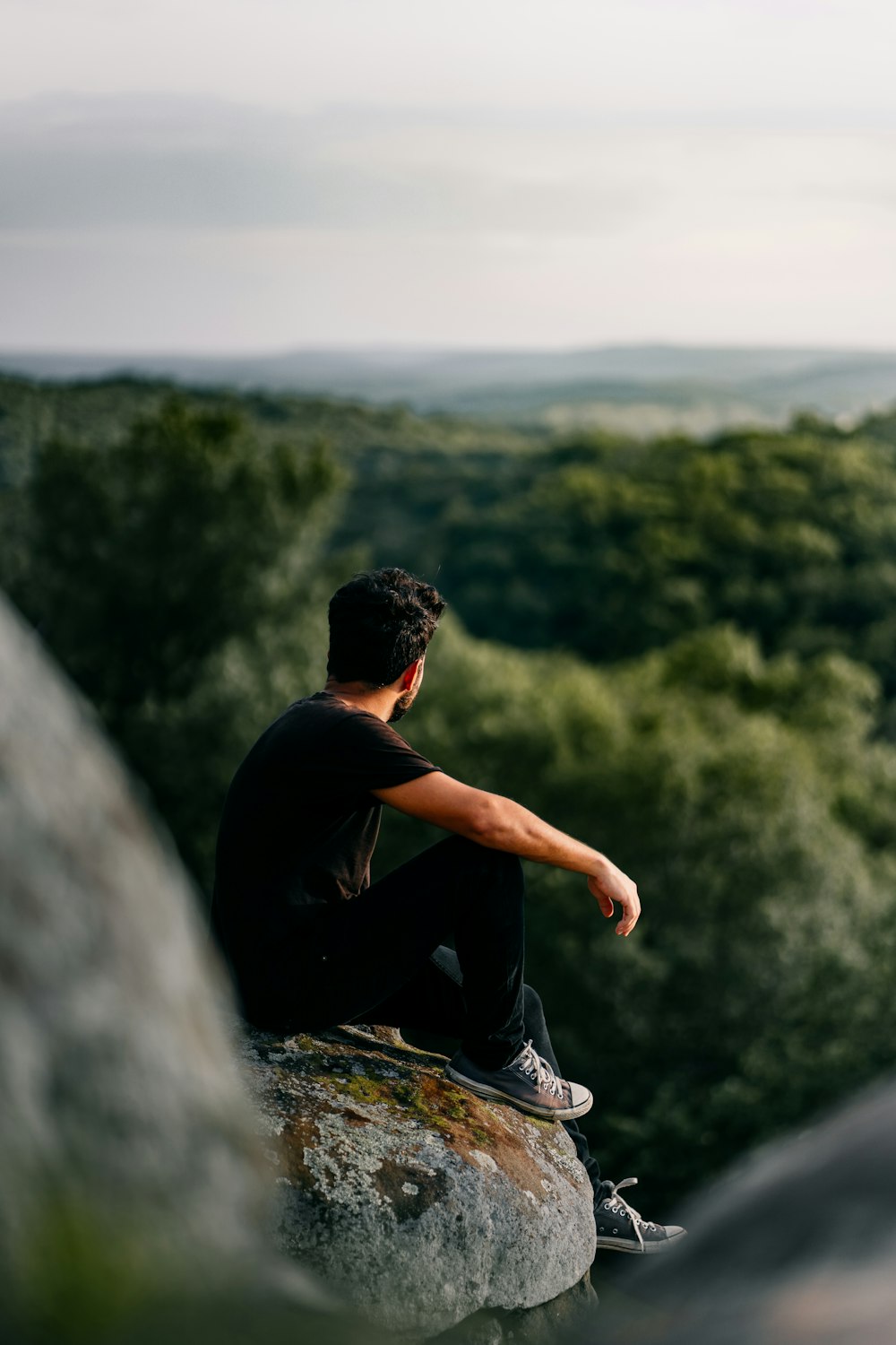 man in black t-shirt sitting on rock during daytime