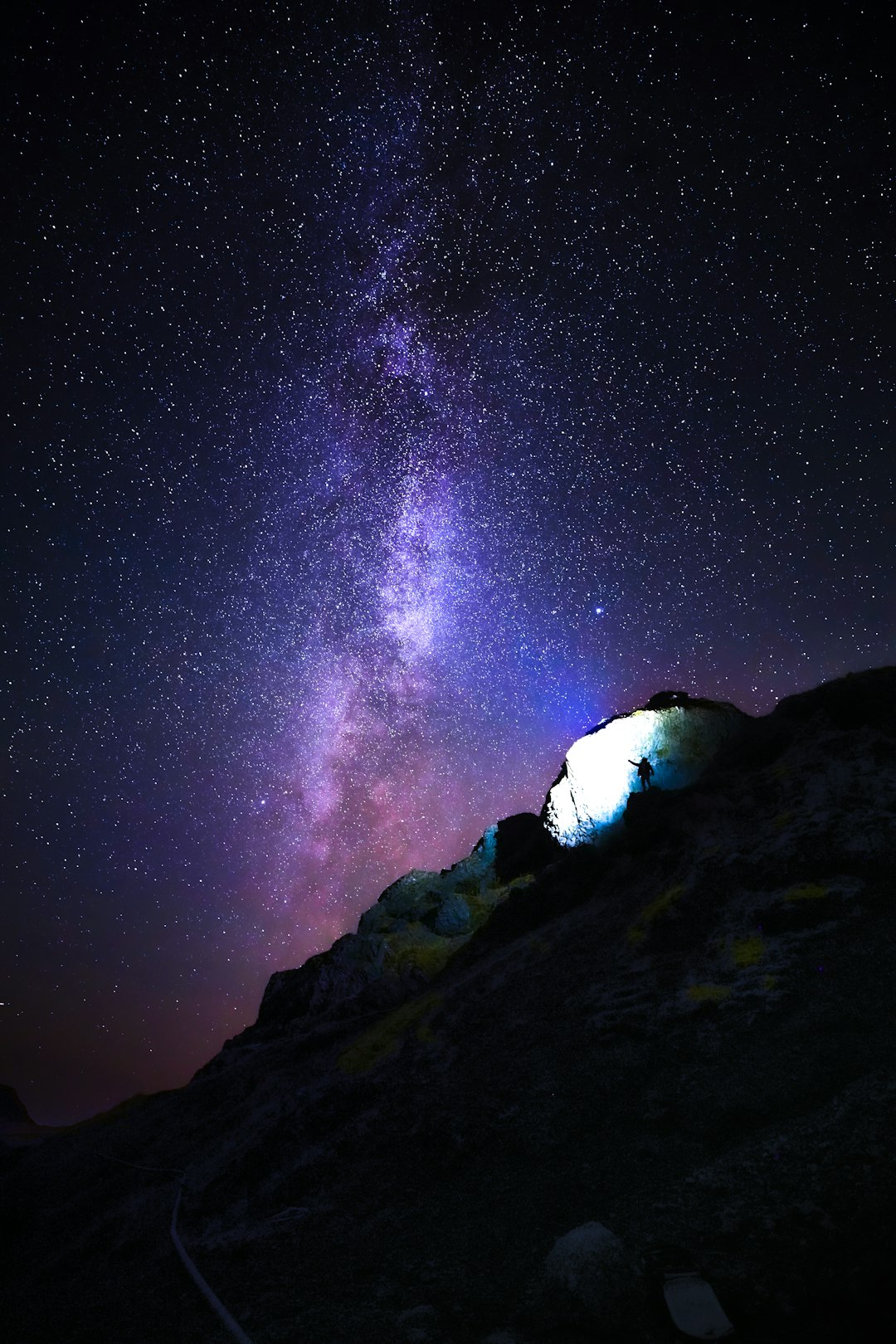 person standing on rock mountain under starry night
