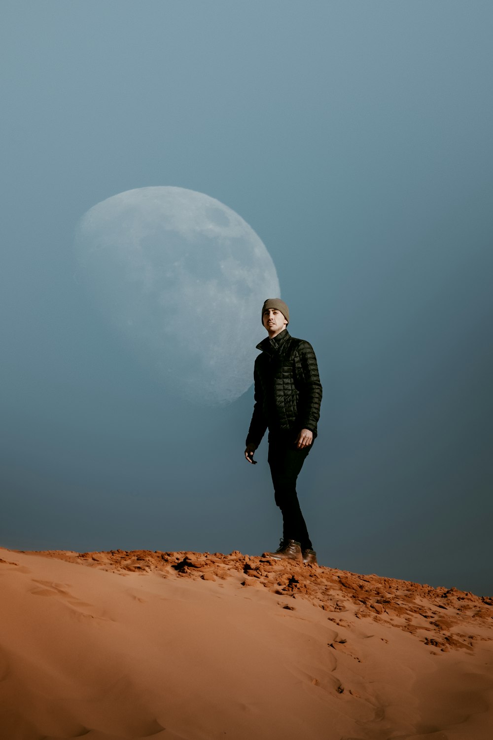 man in black suit standing on brown sand under blue sky during daytime