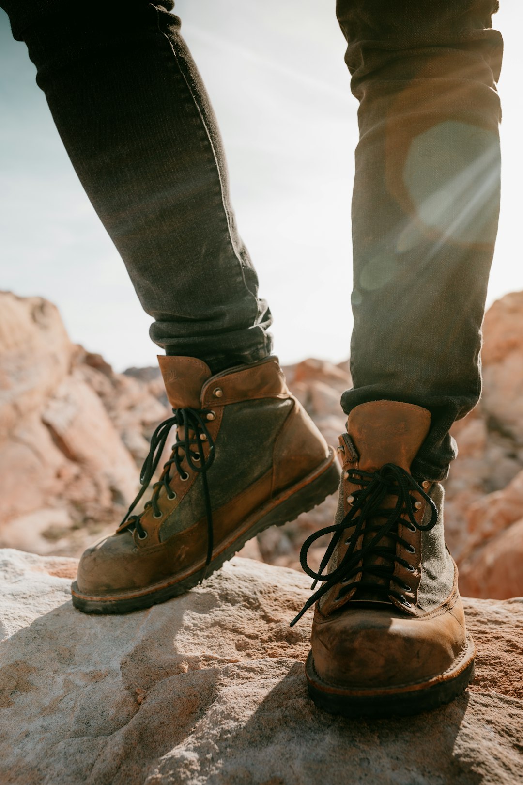 person in brown hiking boots sitting on rock during daytime