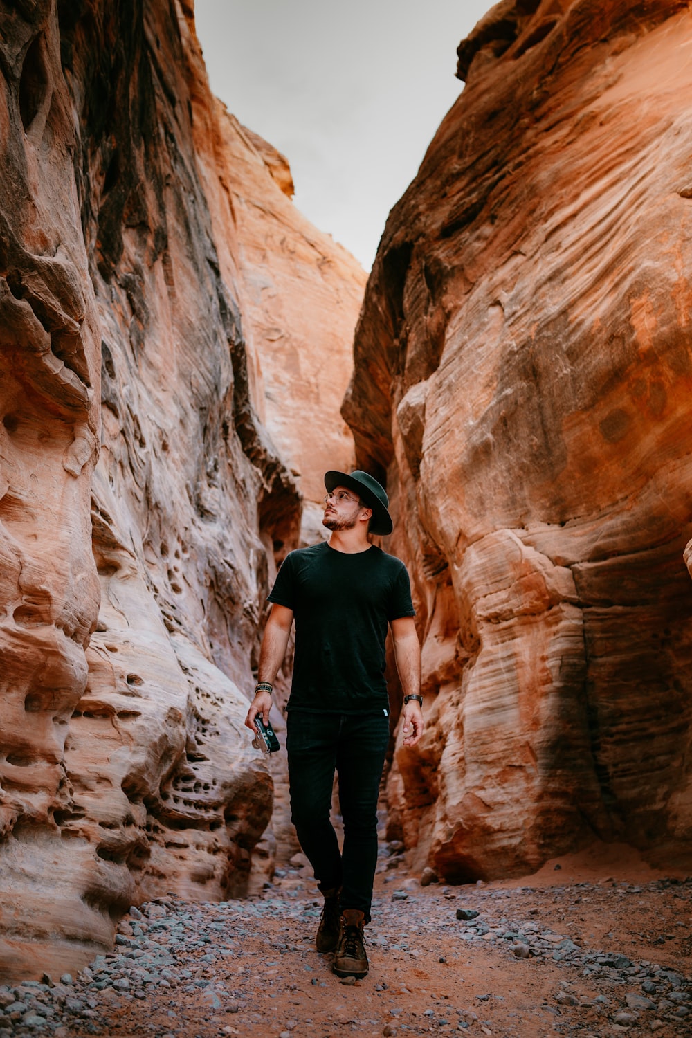 man in black crew neck t-shirt and black pants standing on brown rock formation during
