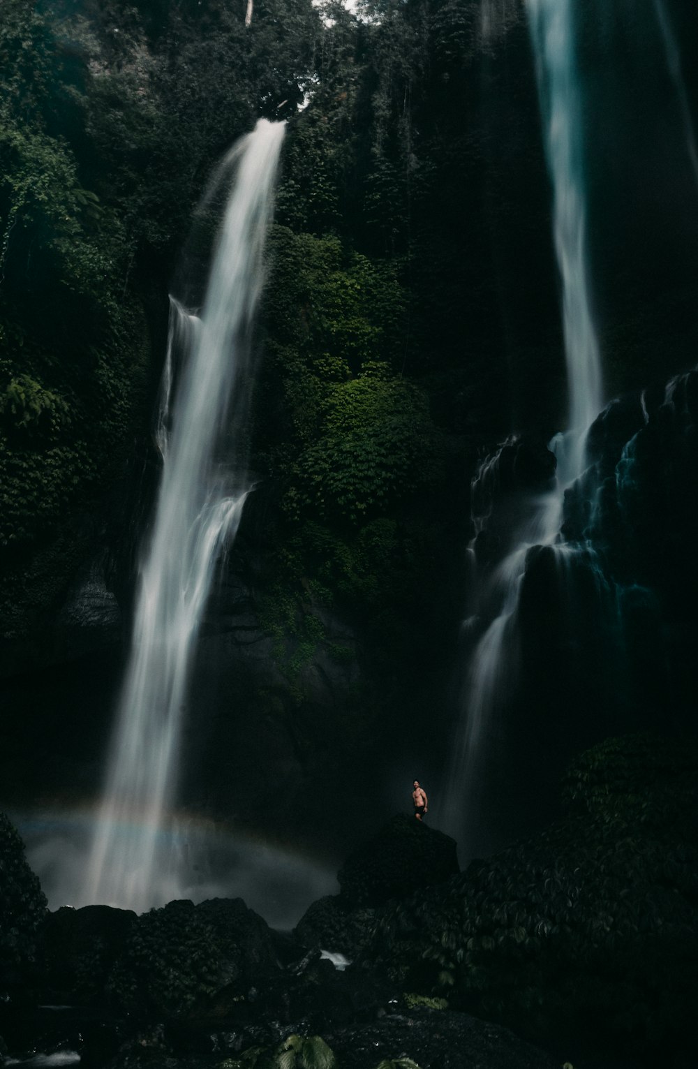 people sitting on rock in front of waterfalls during daytime