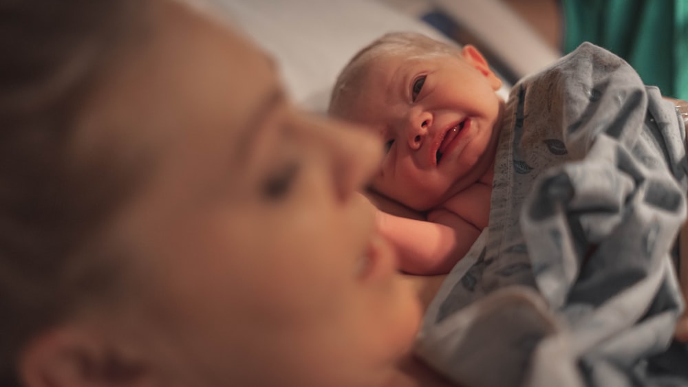 baby in gray shirt lying on bed