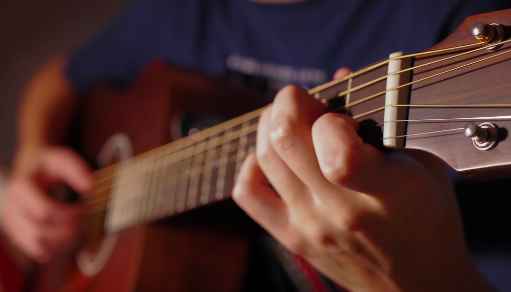 person playing brown acoustic guitar