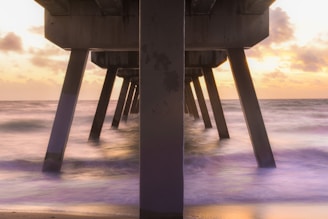 Waterfront pier supported by sturdy concrete pilings at sunset.