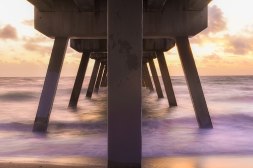Waterfront pier supported by sturdy concrete pilings at sunset.