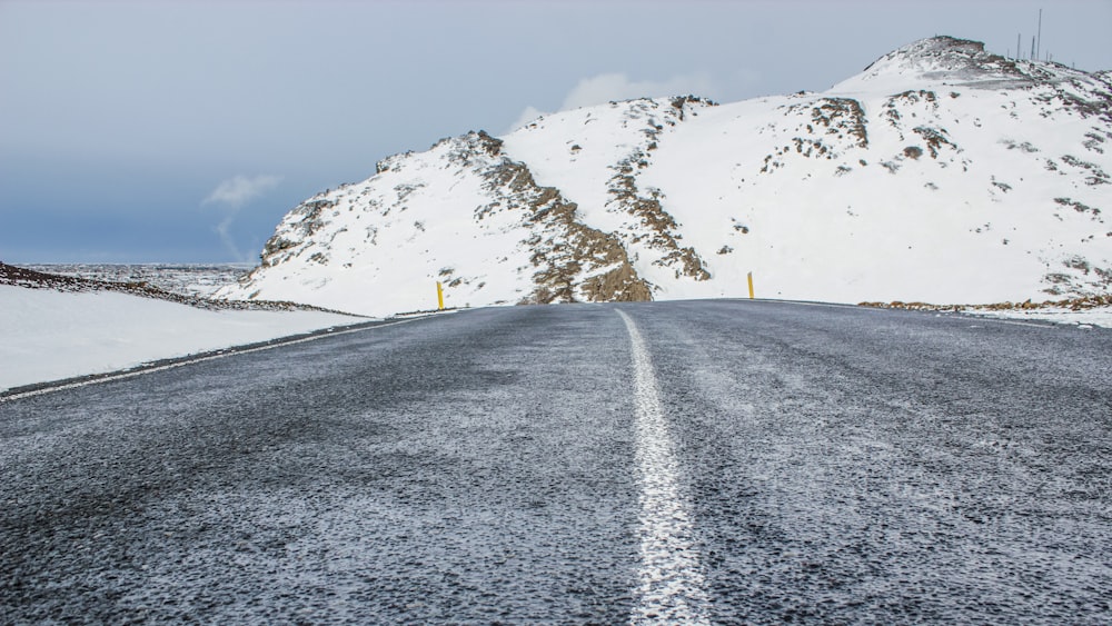 gray asphalt road near snow covered mountain during daytime