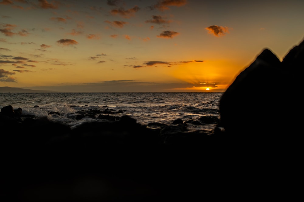 silhouette of rocks on beach during sunset